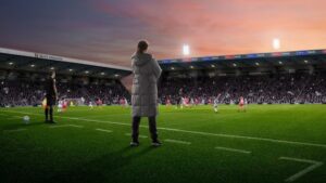 Entraîneur observant un match au bord du terrain dans Football Manager 26